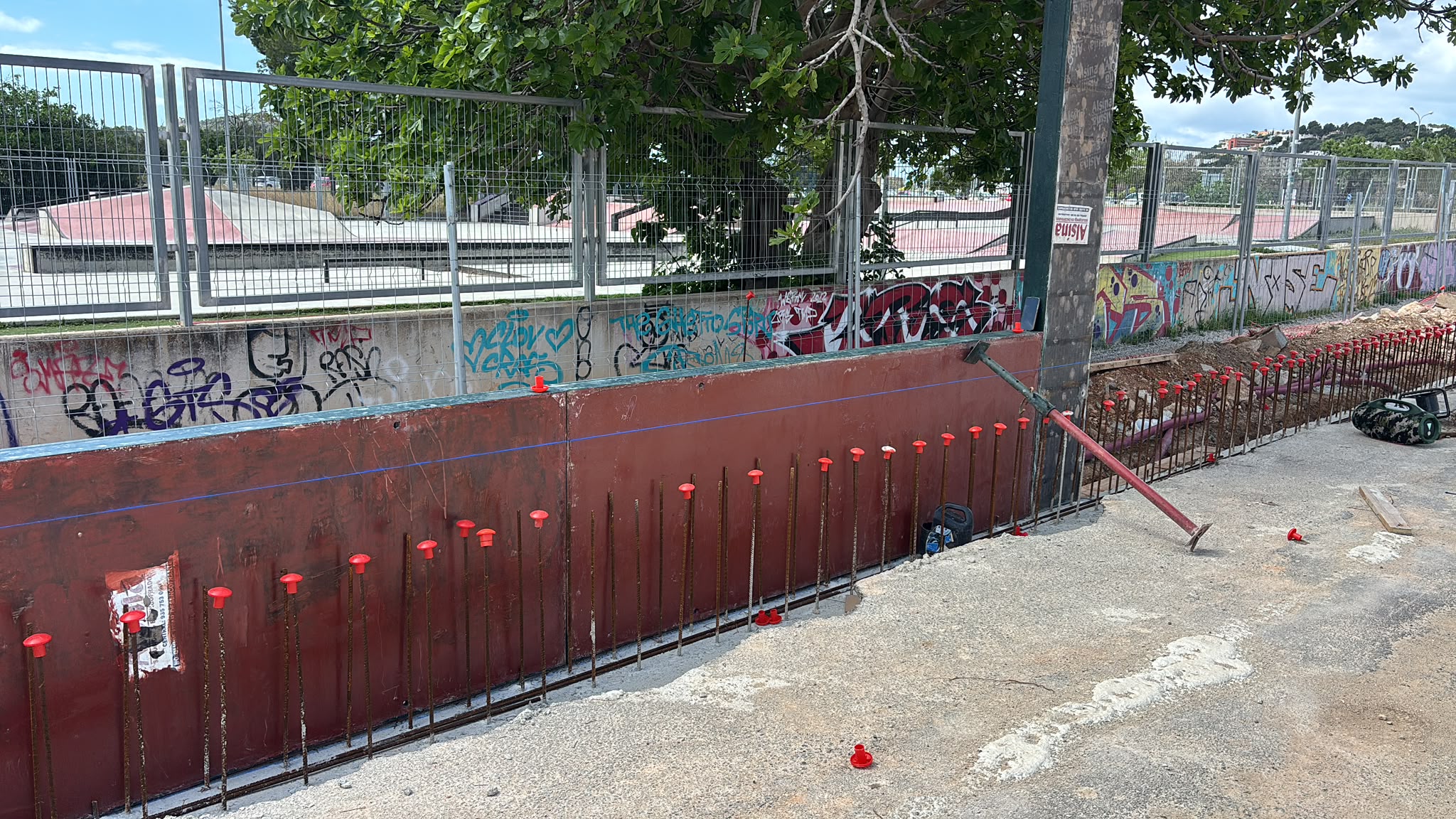Muro de hormigón con esperas de ferralla junto a un carril de skatepark